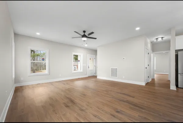 a view of an empty room with a window and wooden floor