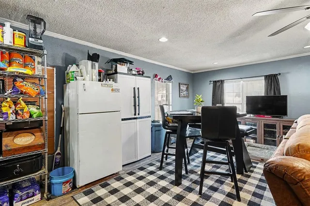 a living room with furniture a flat screen tv and a refrigerator