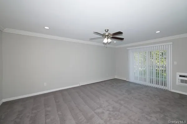 an empty room with a chandelier fan and windows