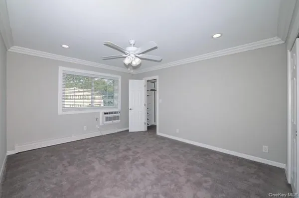an empty room with windows and ceiling fan