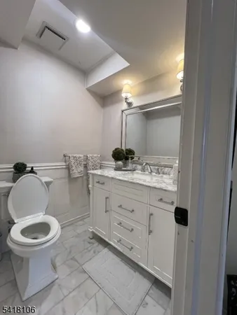 a bathroom with a granite countertop toilet sink and mirror