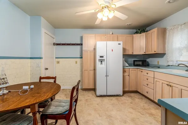 a kitchen with stainless steel appliances granite countertop a refrigerator a sink a stove a dining table and chairs