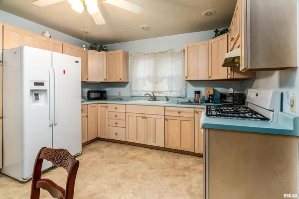 a kitchen with stainless steel appliances granite countertop a stove a refrigerator a sink dishwasher a dining table and chairs with wooden floor