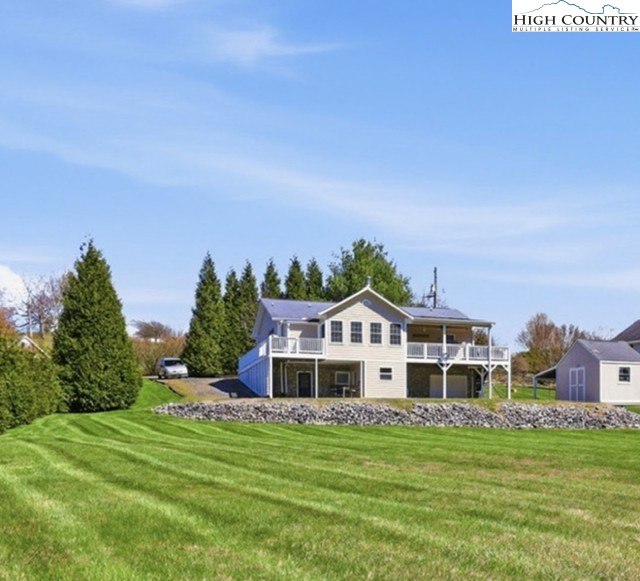 154 Beau Rivage Drive Crumpler, NC 28617 - Photo 11 of 34 a view of a white house with a big yard and potted plants and large trees