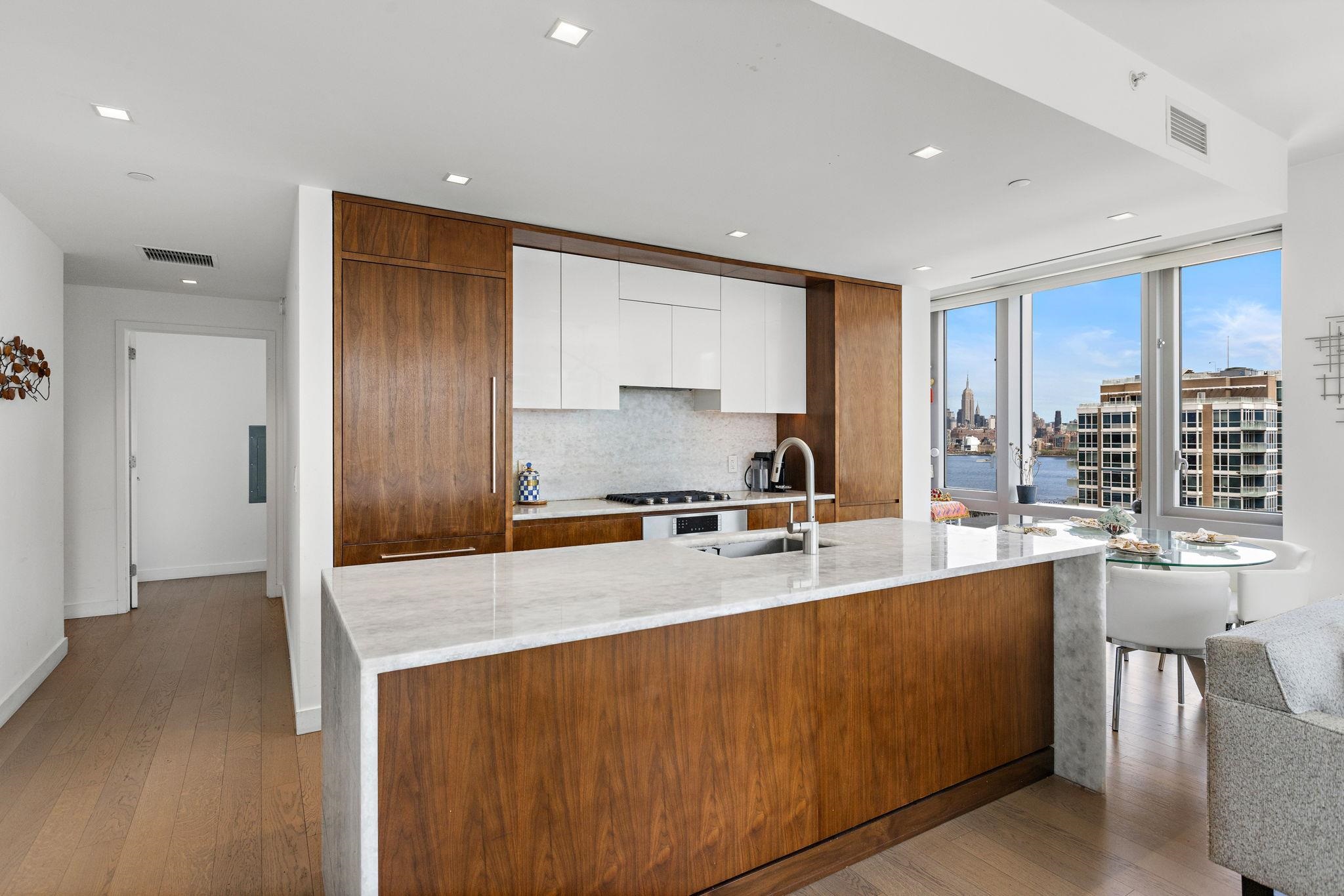 75 Park Lane South, Unit 1607 Jersey City, NJ 07310 - Photo 6 of 20 a large kitchen with stainless steel appliances a large window and a counter space