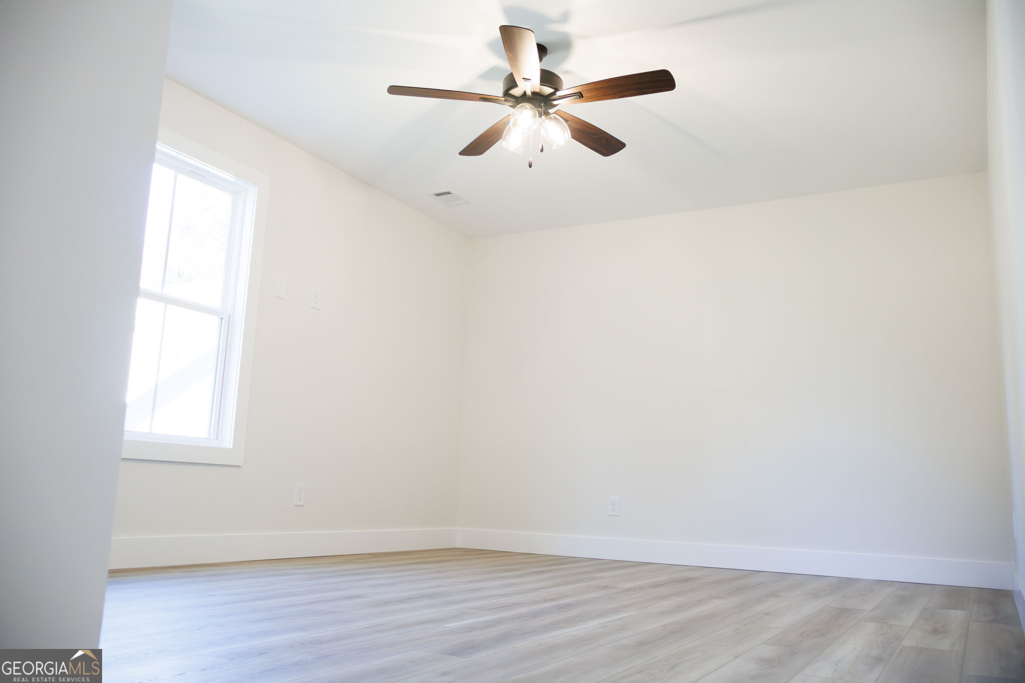 903 Massee Lane Perry, GA 31069 - Photo 19 of 26 an empty room with wooden floor fan and windows