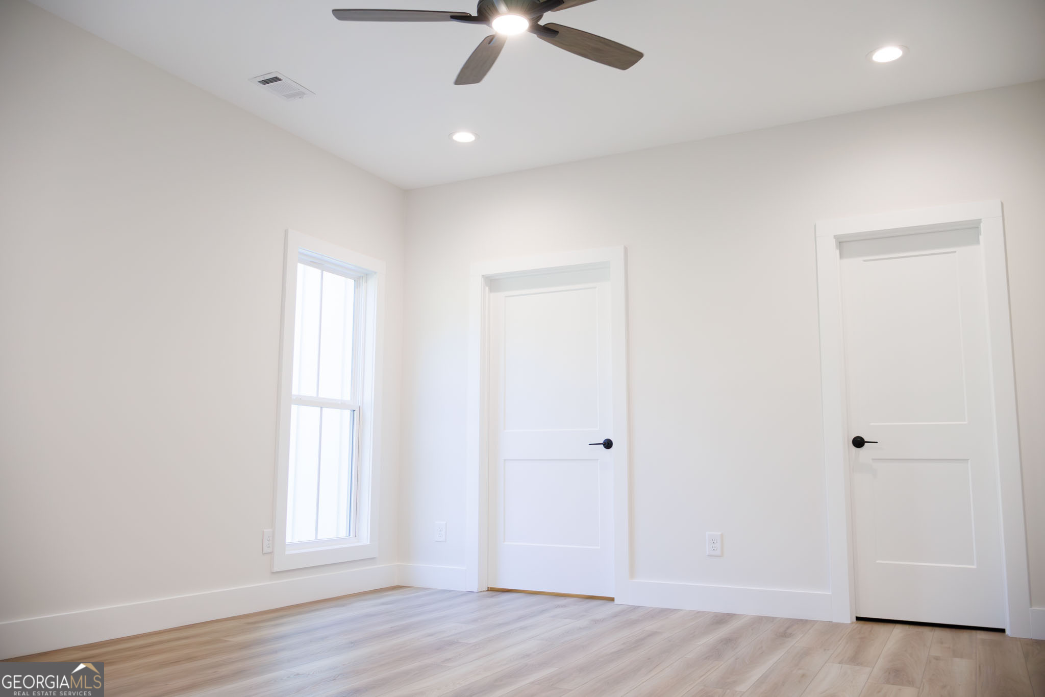 903 Massee Lane Perry, GA 31069 - Photo 23 of 26 an empty room with wooden floor ceiling fan and windows