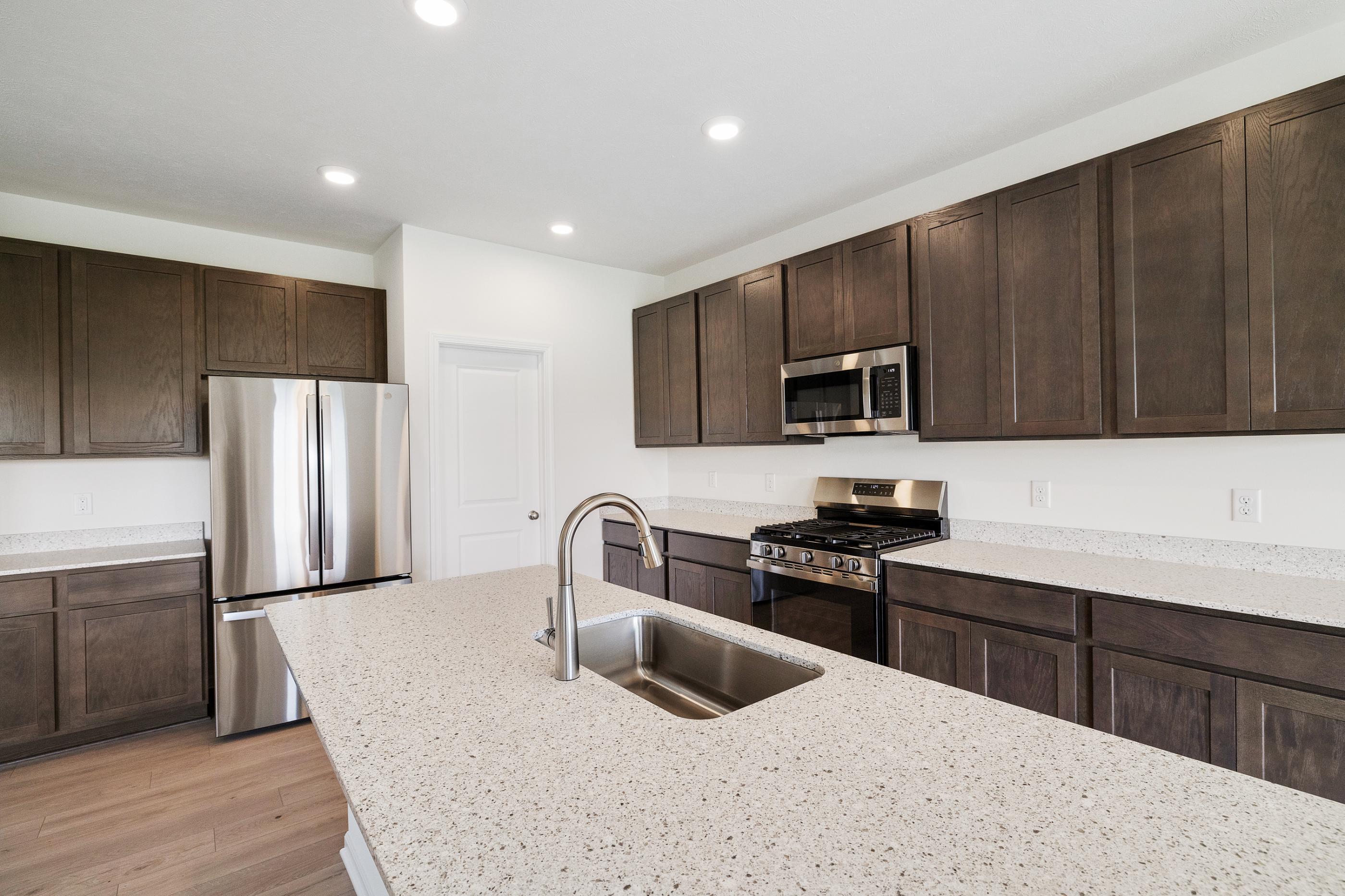 6821 Tucson Road Schererville, IN 46375 - Photo 7 of 24 a kitchen with granite countertop a refrigerator stove a sink and dishwasher with wooden floor