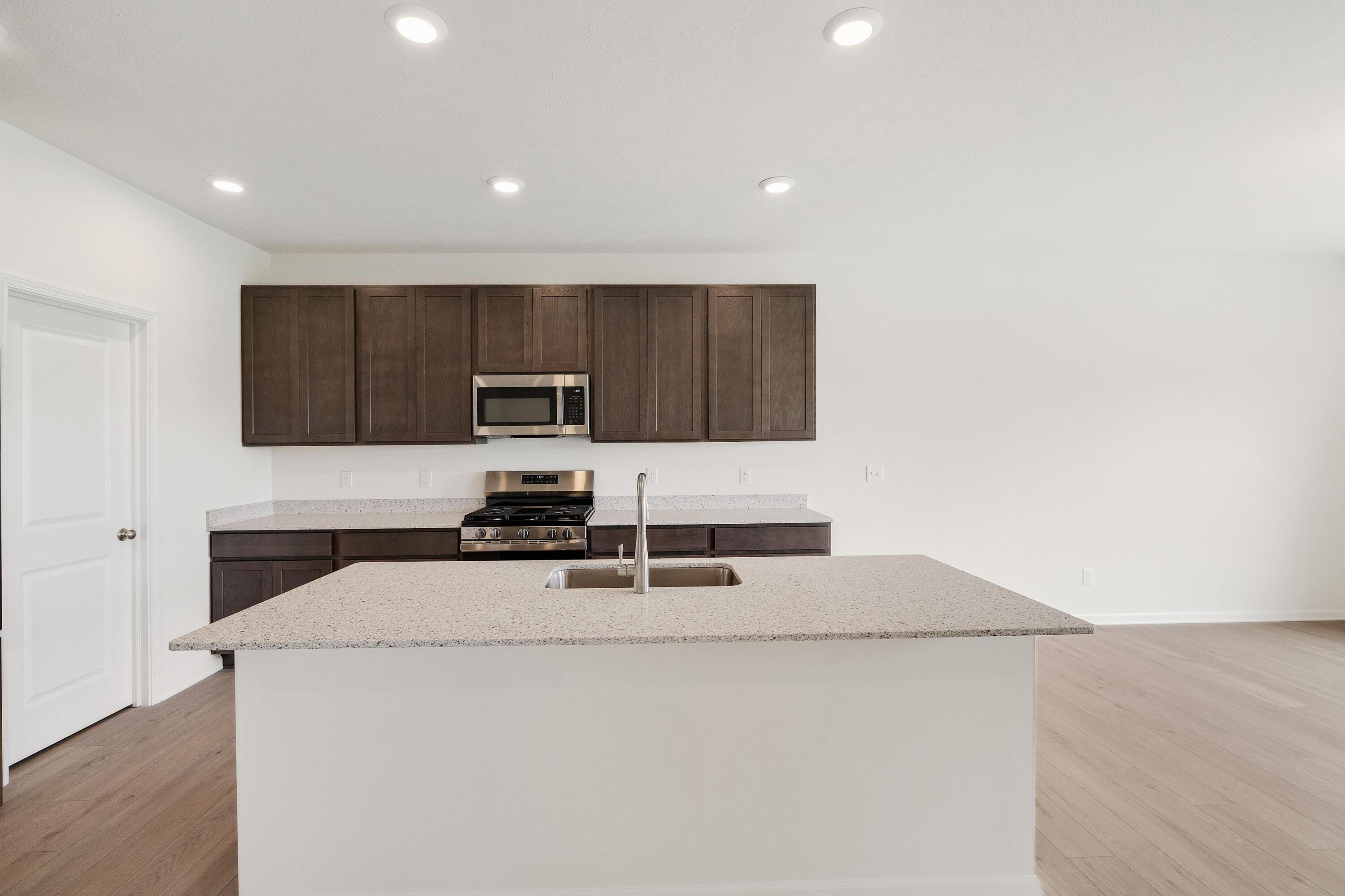 6821 Tucson Road Schererville, IN 46375 - Photo 8 of 24 a kitchen with granite countertop a stove a sink and a microwave