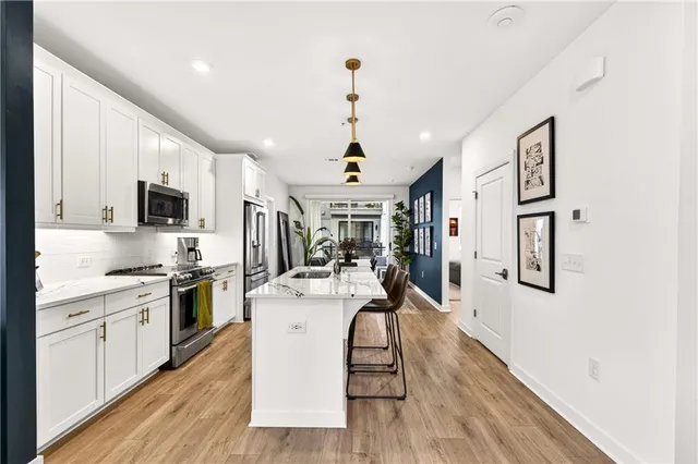 a very nice looking kitchen with granite countertop a stove top oven a sink dishwasher and a refrigerator with wooden floor