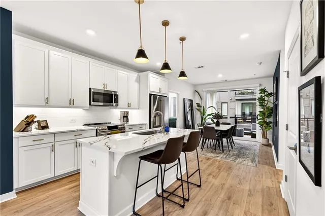 a kitchen with stainless steel appliances kitchen island granite countertop a stove a sink a dining table and chairs with wooden floor