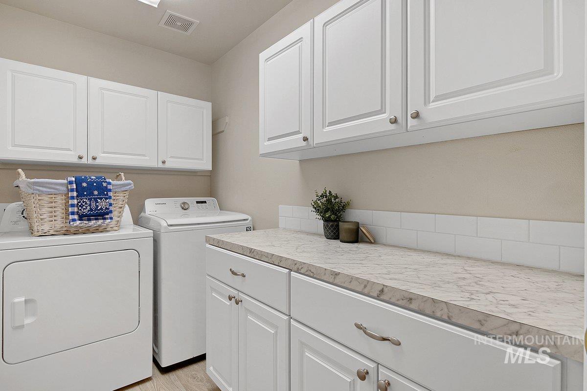725 North Eagle Road Eagle, ID 83616 - Photo 23 of 45 Dedicated laundry space featuring white cabinetry, light-toned countertops, and a subway tile backsplash