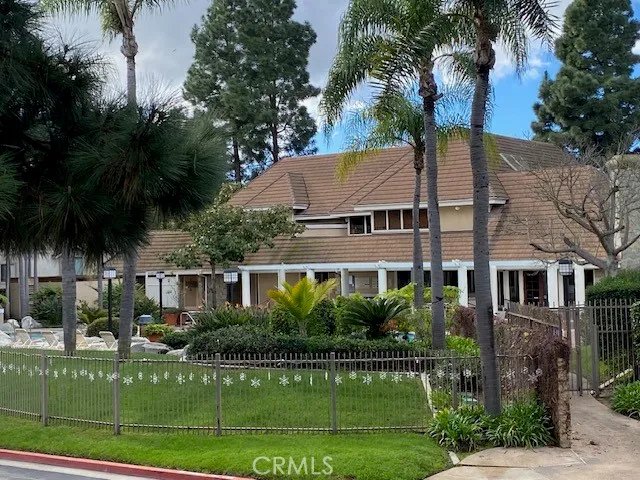 a view of a white house next to a yard with palm trees