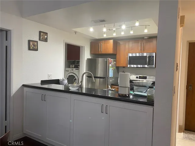 a kitchen with stainless steel appliances granite countertop a sink and a refrigerator