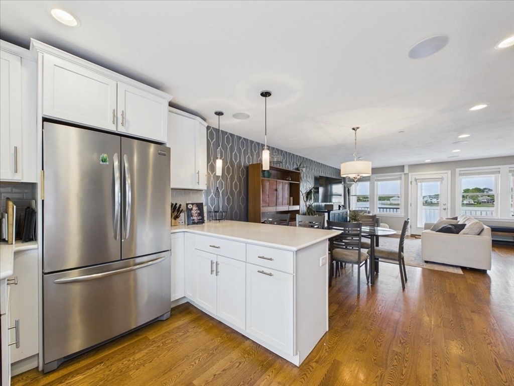 7 Bay Street, Unit 3 Hull, MA 02045 - Photo 16 of 40 a kitchen with stainless steel appliances a refrigerator a stove a sink a dining table and chairs with wooden floor