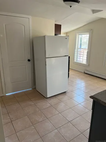 a view of a refrigerator in kitchen and an empty room
