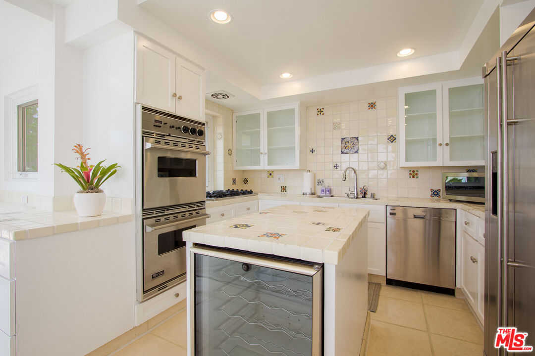1244 Stradella Road Los Angeles, CA 90077 - Photo 9 of 18 a kitchen with a sink a stove a refrigerator and white cabinets