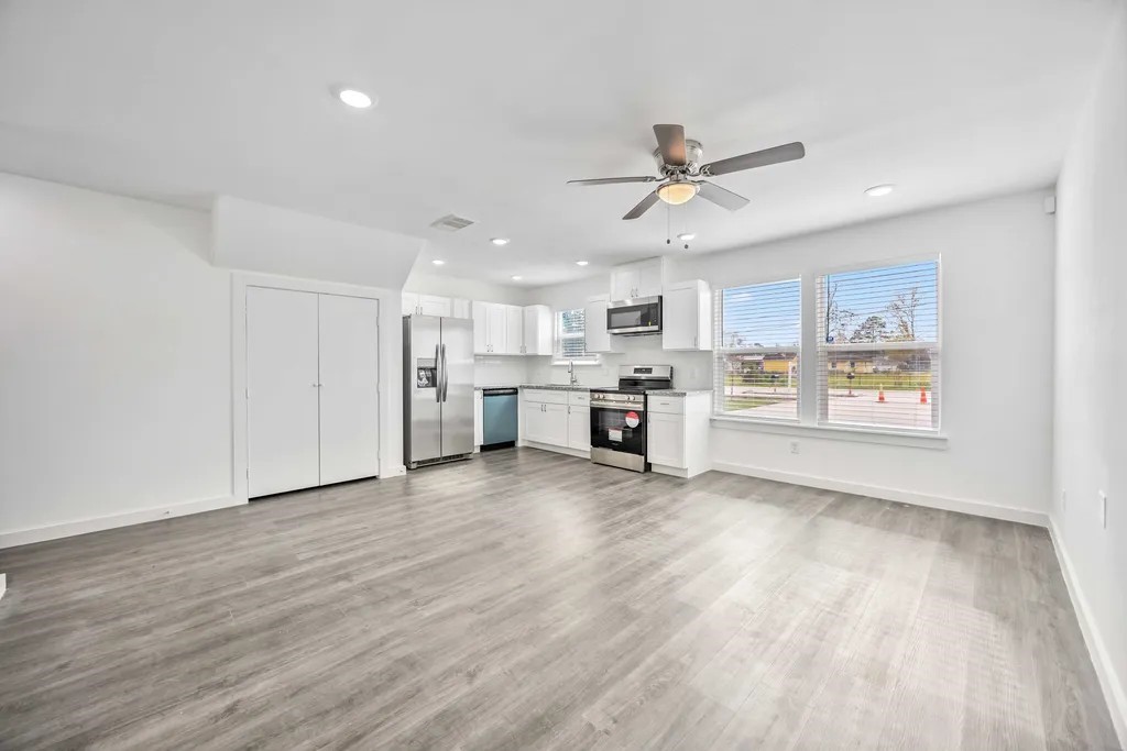 7811 Laura Koppe Road, Unit A Houston, TX 77028 - Photo 4 of 23 a view of a kitchen with a stove cabinets a ceiling fan and wooden floor