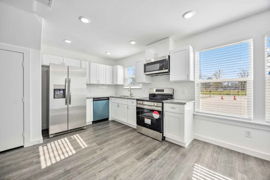 7811 Laura Koppe Road, Unit A Houston, TX 77028 - Photo 5 of 23 a kitchen with granite countertop a refrigerator and a stove top oven
