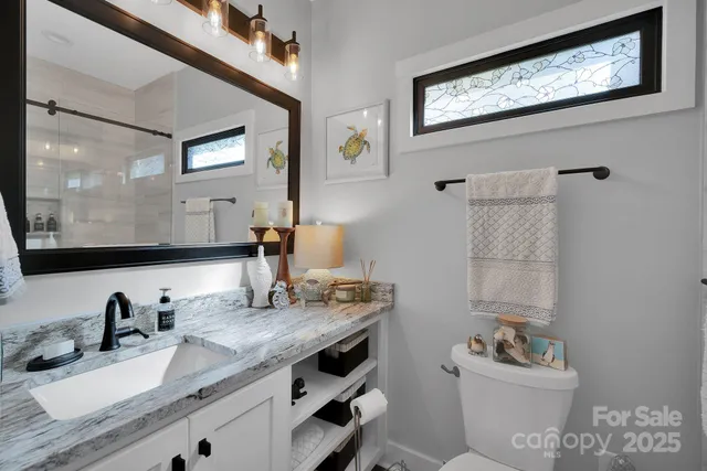 a bathroom with a granite countertop sink mirror vanity and toilet