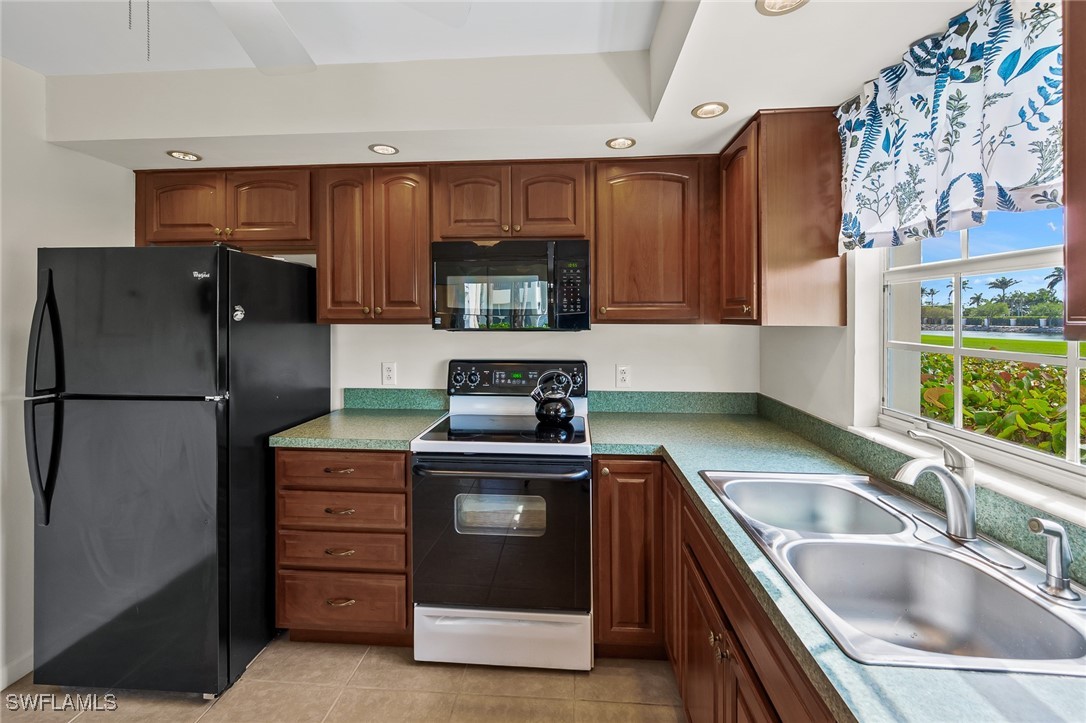 14995 Rivers Edge Court, Unit 151 Fort Myers, FL 33908 - Photo 7 of 18 a kitchen with stainless steel appliances granite countertop a refrigerator and a sink