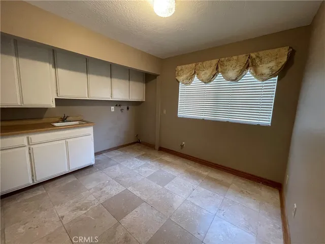 a view of a kitchen with white cabinets and a window