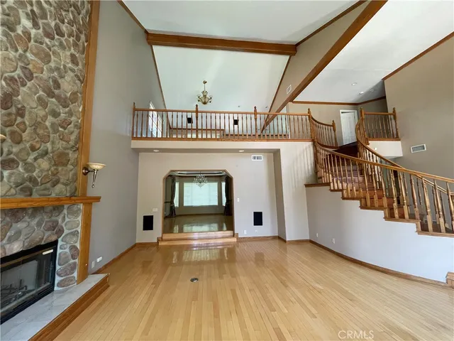 a view of an empty room with wooden floor fireplace and a window