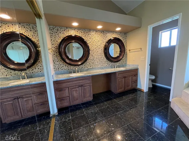a bathroom with a granite countertop double vanity and a mirror