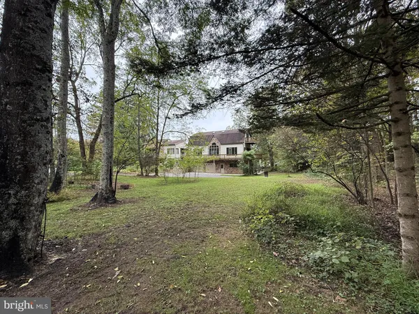 a view of a white house with a big yard and large trees