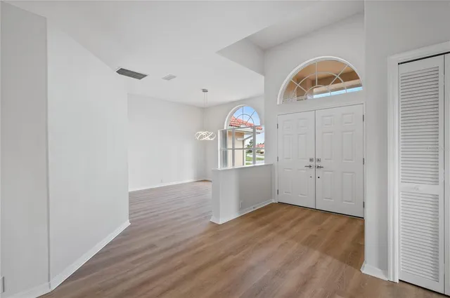 an empty room with wooden floor cabinet and windows