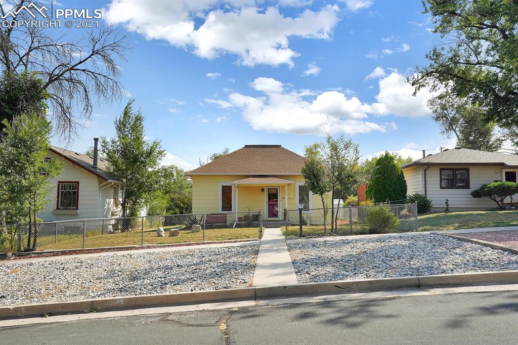 1225 Alexander Road Colorado Springs, CO 80909 - Photo 3 of 26 a front view of a house with a yard and trees