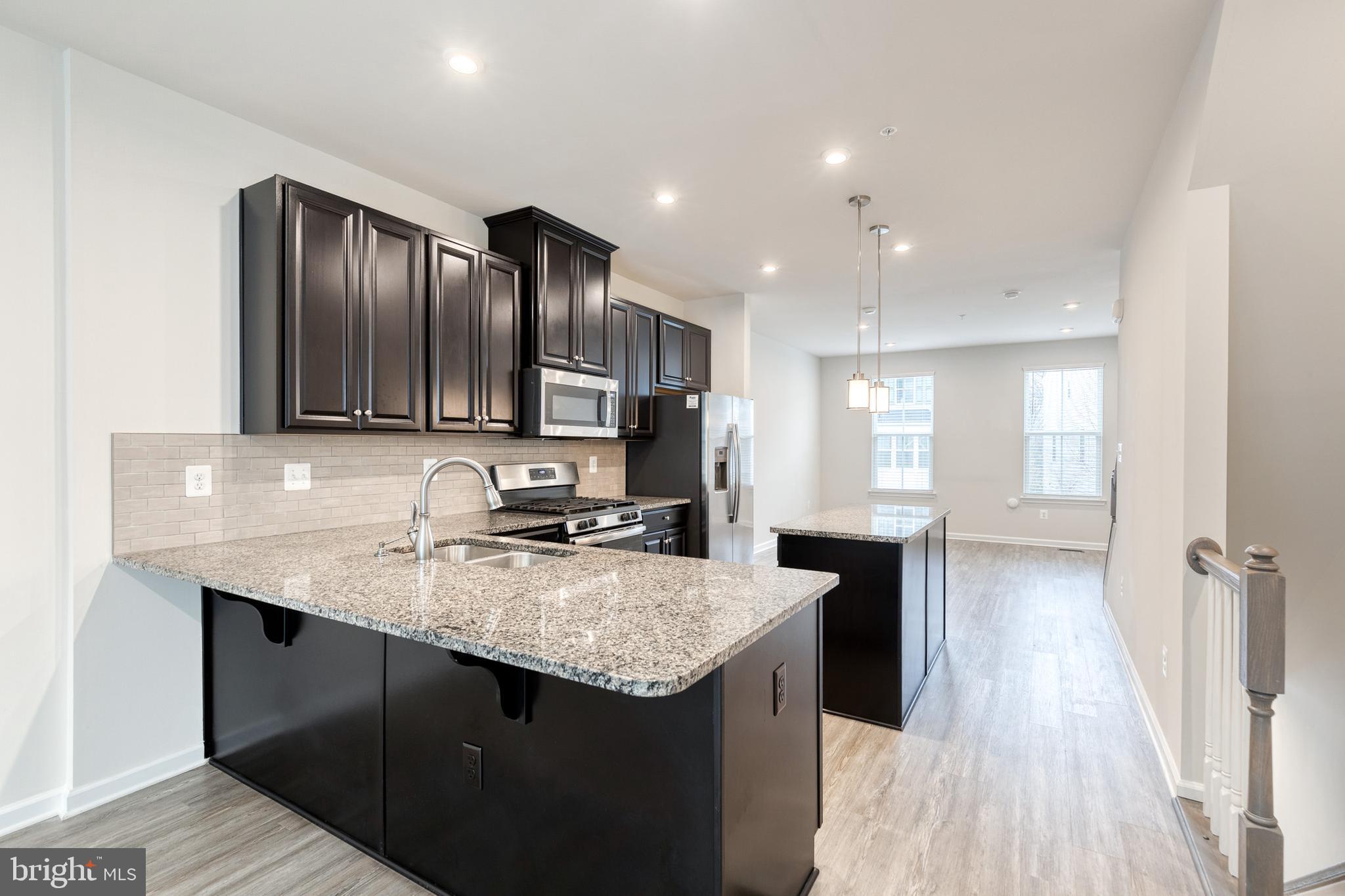 1438 Strahorn Road Hanover, MD 21076 - Photo 4 of 19 a kitchen with a sink dishwasher a refrigerator with wooden cabinets and floor