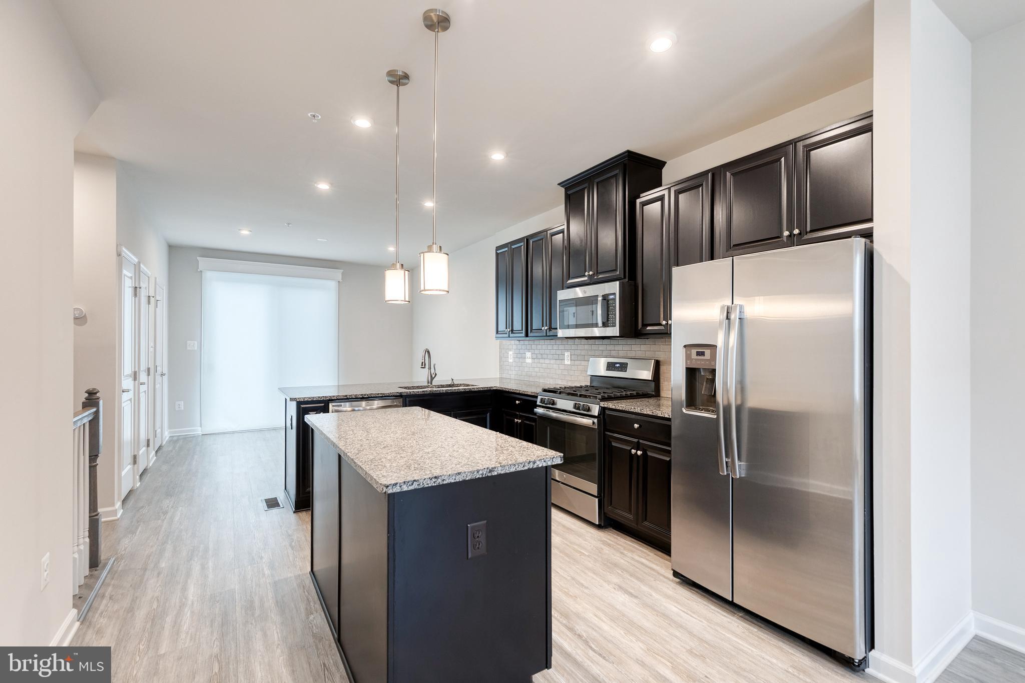 1438 Strahorn Road Hanover, MD 21076 - Photo 6 of 19 a kitchen with kitchen island granite countertop stainless steel appliances cabinets a sink and a refrigerator