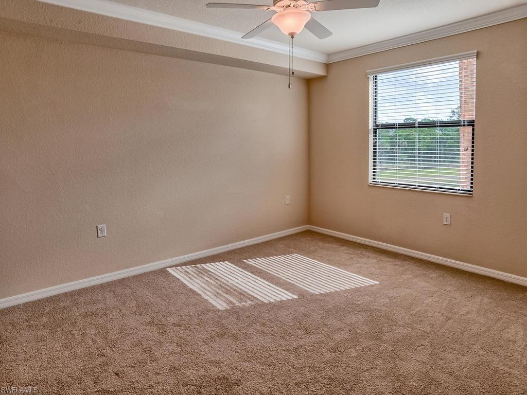 9566 Trevi Court, Unit 4934 Naples, FL 34113 - Photo 7 of 27 an empty room with a chandelier fan and windows