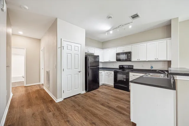 a kitchen with granite countertop a refrigerator stove top oven and sink