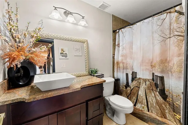 a bathroom with a granite countertop sink mirror vanity and toilet