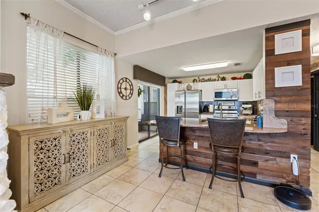 a kitchen with stainless steel appliances kitchen island granite countertop a table chairs in it and a large window