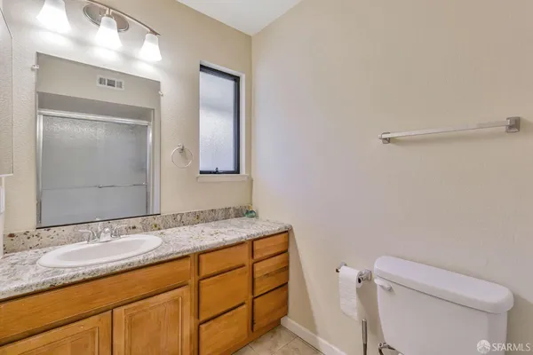 a bathroom with a granite countertop sink toilet and mirror