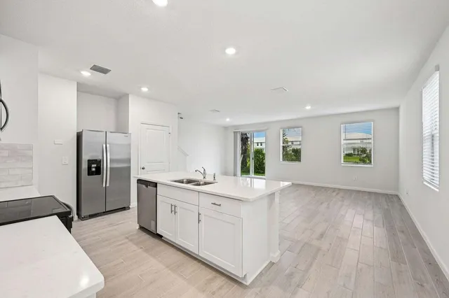 a kitchen with stainless steel appliances a sink a stove a refrigerator cabinets and a window