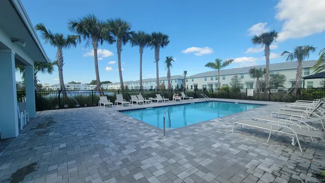 a view of a swimming pool with a yard and palm trees