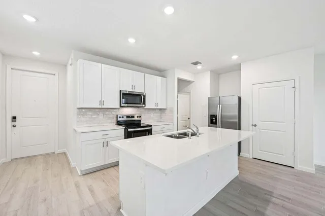 a kitchen with white cabinets and stainless steel appliances