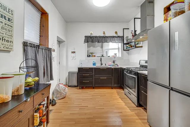 a kitchen with stainless steel appliances granite countertop a stove top oven a refrigerator and a dining table with wooden floor