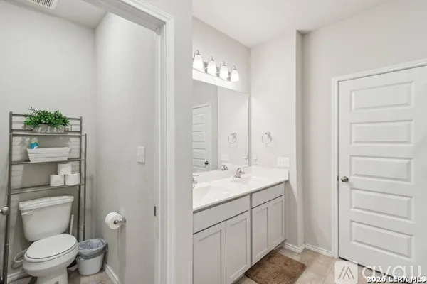 a en suite bathroom with a granite countertop sink toilet and a mirror