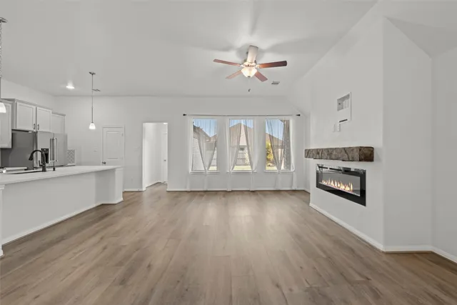 a view of kitchen with granite countertop a stove top oven a sink and wooden floors