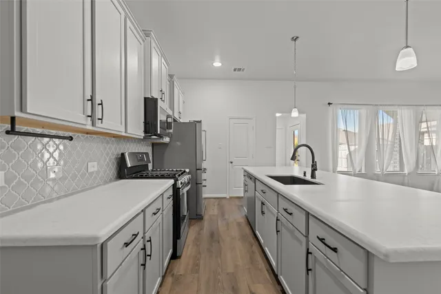 a kitchen with stainless steel appliances a sink stove and cabinets