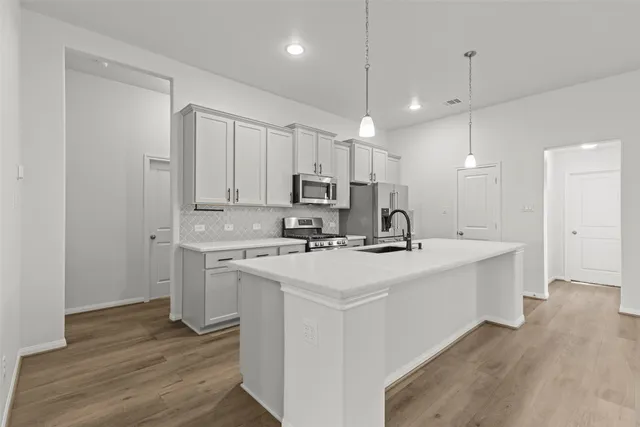 a kitchen with kitchen island a sink stainless steel appliances and cabinets