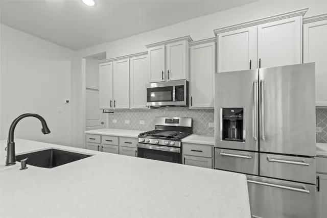 a kitchen with granite countertop a refrigerator and a stove top oven