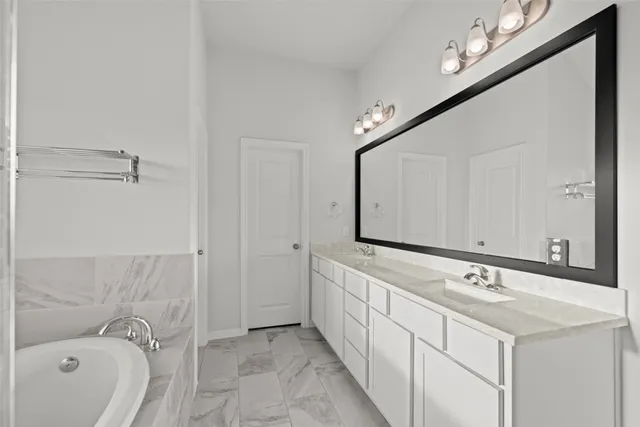 a bathroom with a double vanity sink and mirror with bathtub