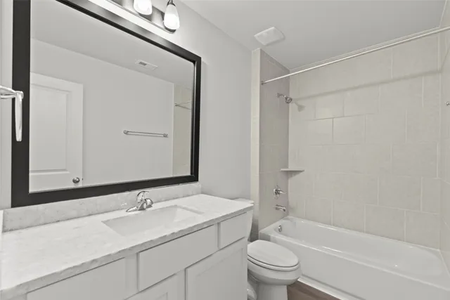 a bathroom with a granite countertop sink a toilet and a bathtub