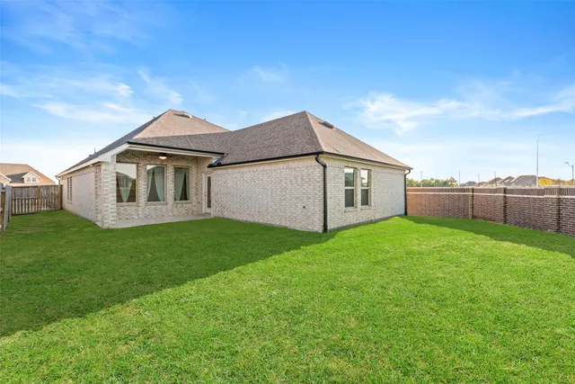 a view of a yard in front of a house with plants and large tree